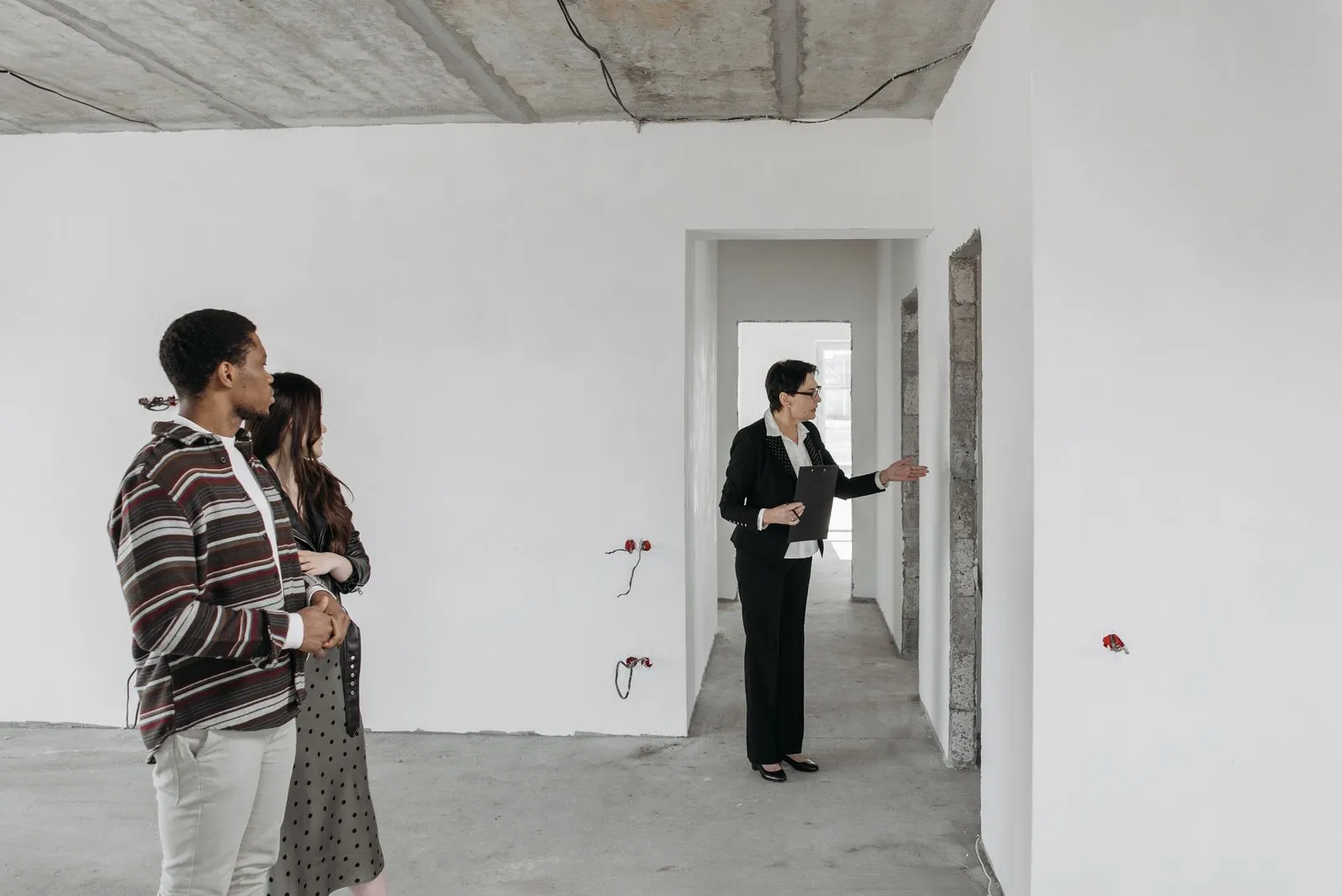 A couple explores an unfinished apartment with a real estate agent, considering property purchase options.